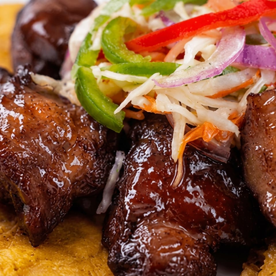 Glazed grilled meat chunks topped with shredded cabbage, peppers, carrots, and onions, served over golden fried plantains.
